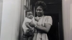 Image of Maxine Grant in a doorway holding a baby