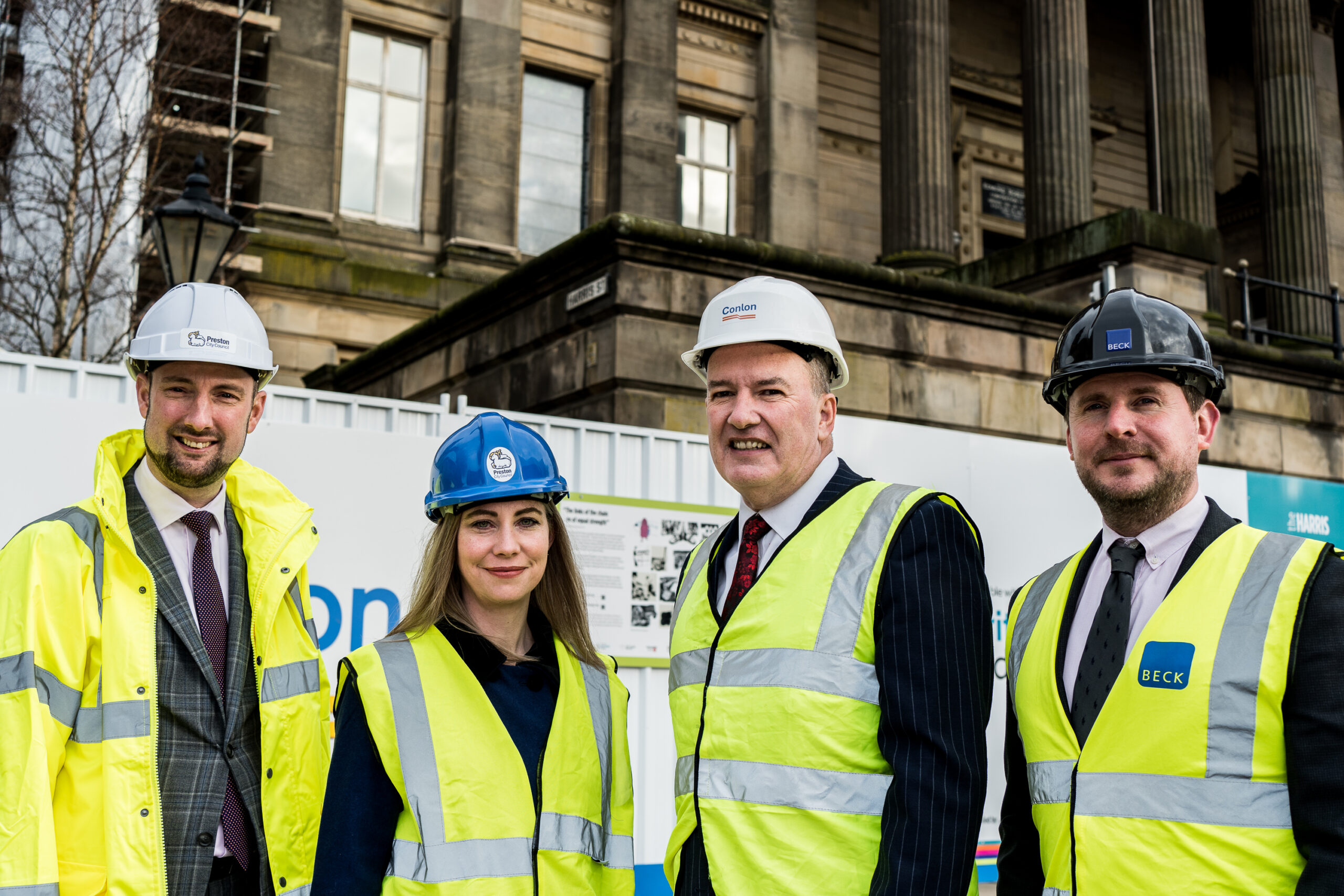 A group of people representing The Harris, Conlon and Beck stood outside the building with hard hats.