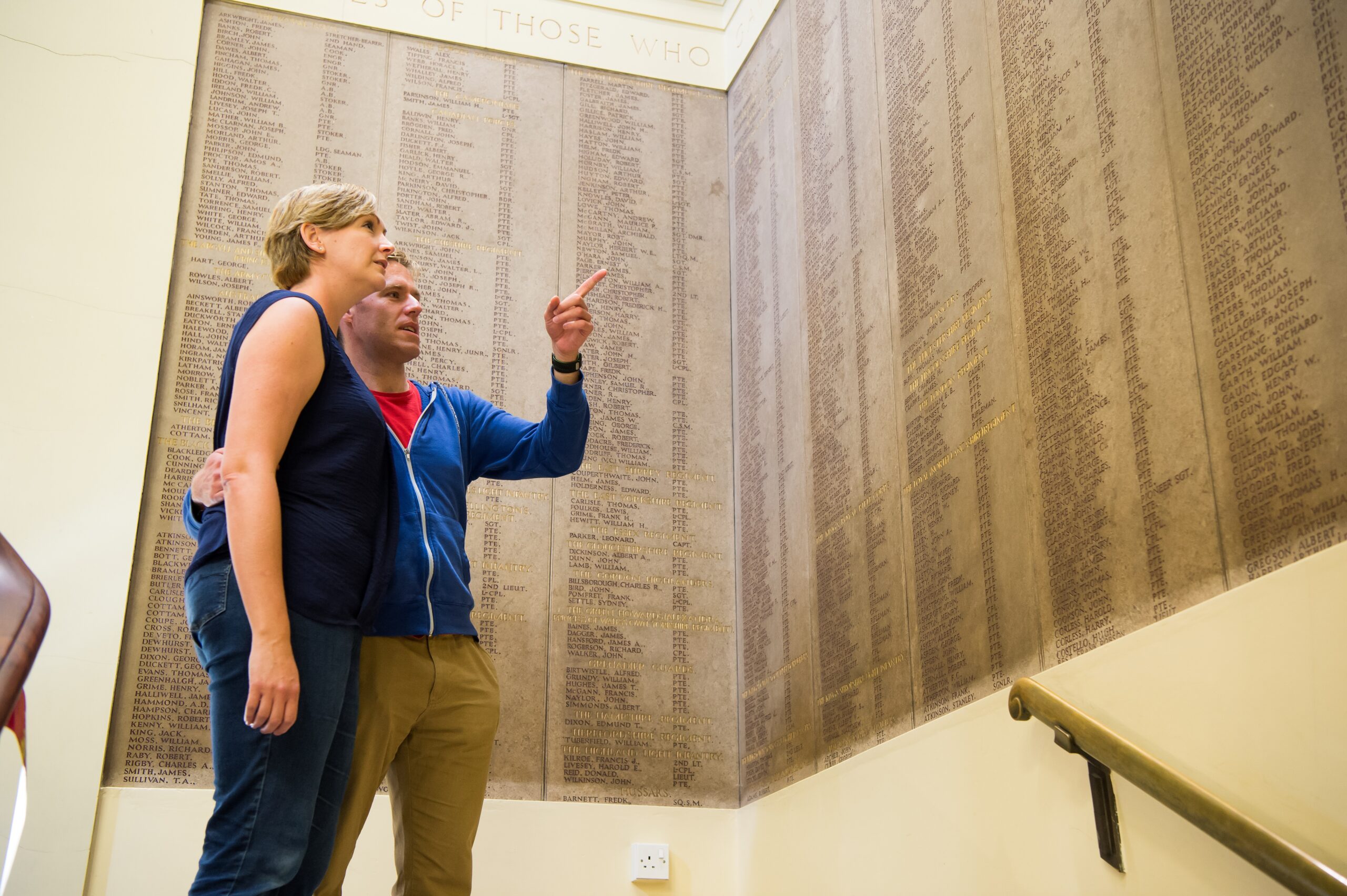 Image of two people pointing to the roll of honour