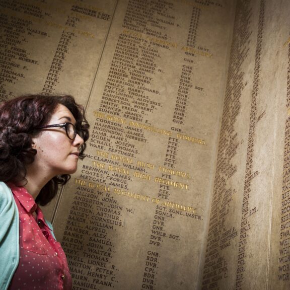 A person with short brown hair and glasses looks up towards the Roll of Honour.