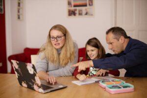 Image of a woman and a man sat round a computer pointing with a young child.