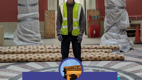 A person wearing a hard hat with a high vis jacket stands in the rotunda space of the Harris.
