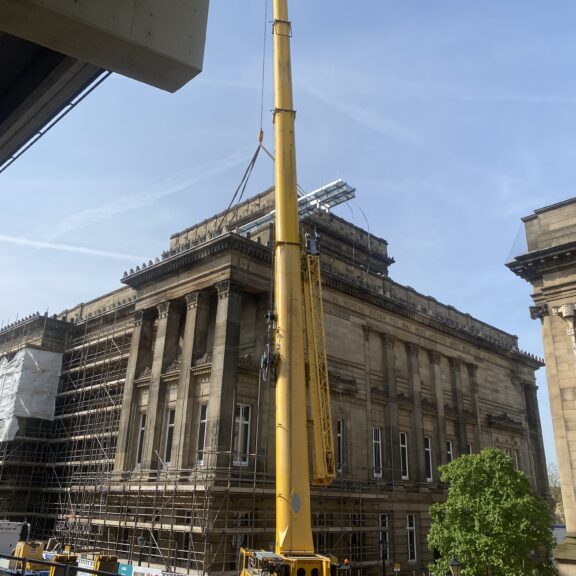 Image of a large yellow crane above The Harris building