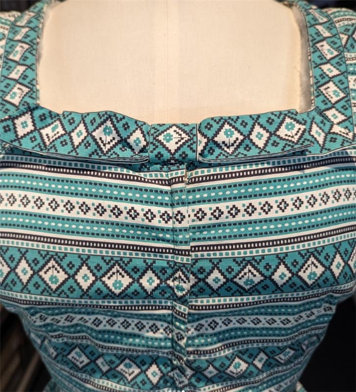 A close up of a white and green geometric print dress.