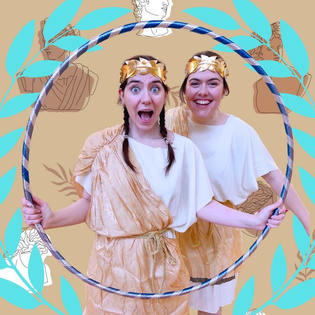 Two people holding a hula hoop dressed as Greek Olympians.