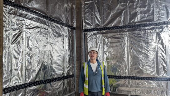 A person wearing protective construction gear stood in front of a containment wall