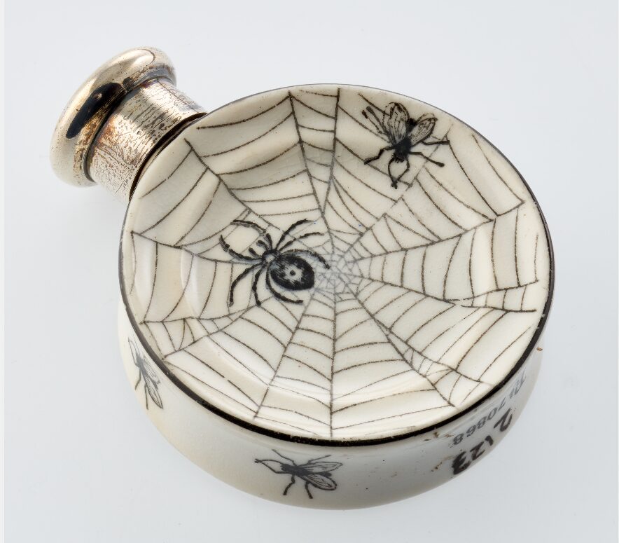 White scent bottle featuring spider and cobwebs.