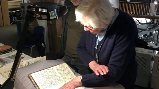 Two people study a text from the Harris' collection.