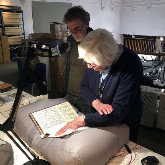 Two people study a text from the Harris' collection.