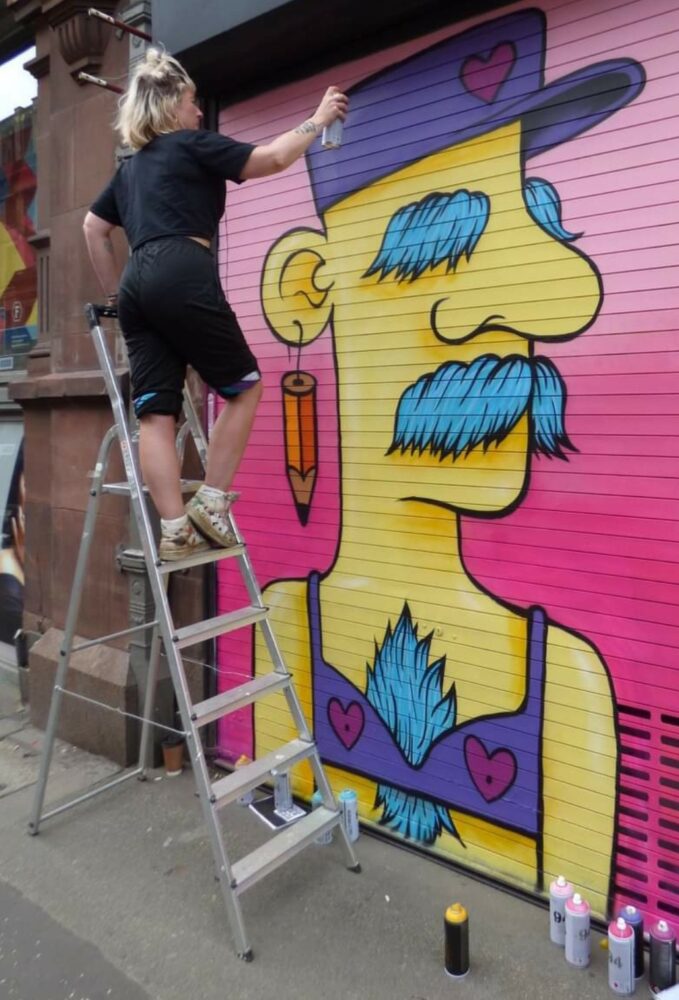 A person spray painting a character onto shutters.