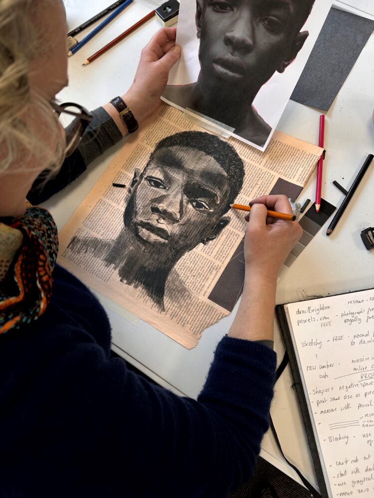 A person sketching a portrait based on a photograph.