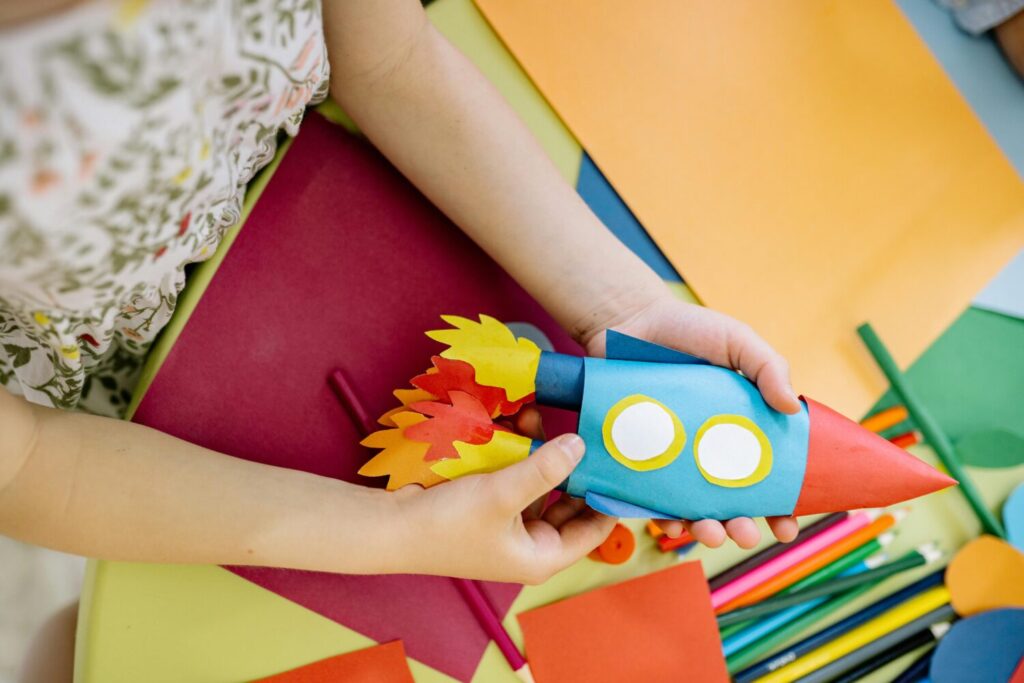 A child crafting a colourful rocket out of card