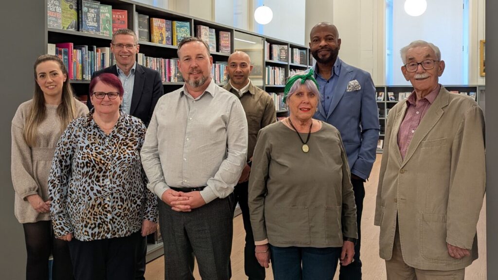 A group of people stood between library shelving.