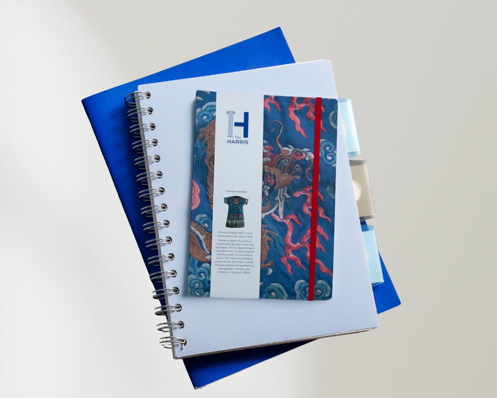 A stack of notepads featuring a blue notepad on top with a Chinese dragon pattern.