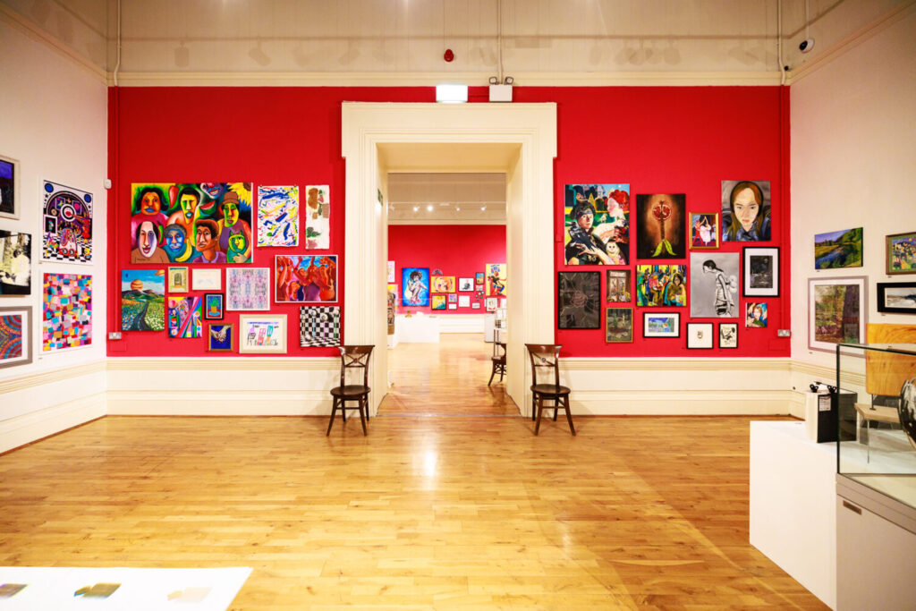 Vibrant artworks on display on a hot pink wall