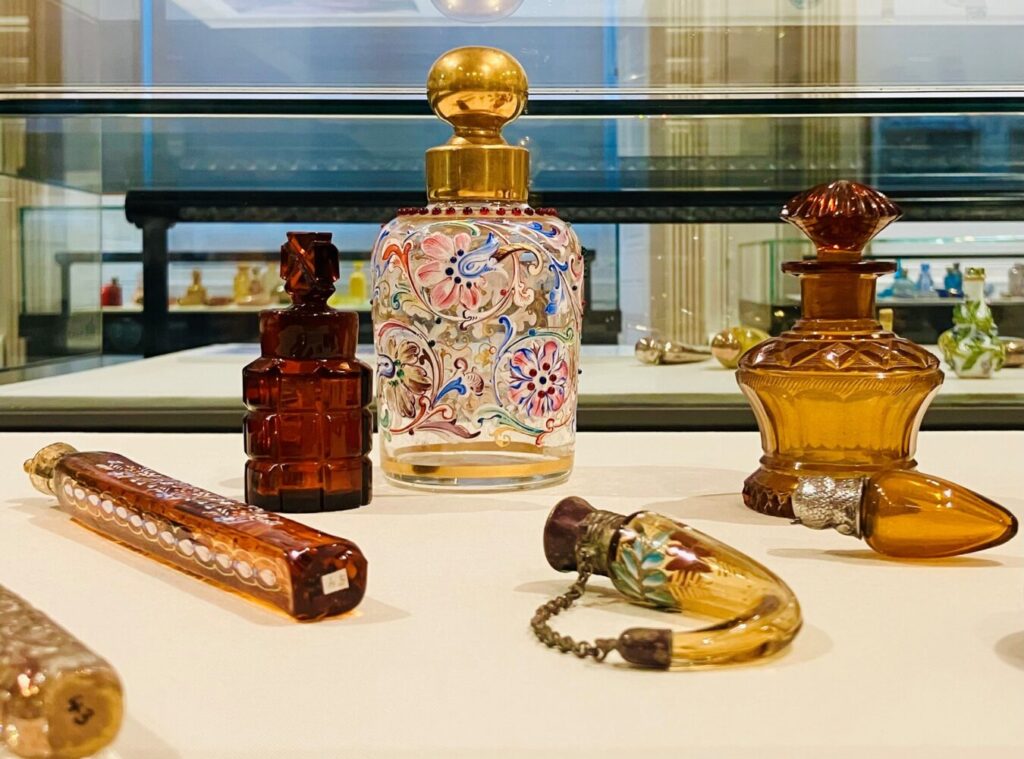 Elegant vintage perfume bottles displayed on a shelf, featuring intricate designs and vibrant colors. The scene conveys a sense of luxury and nostalgia.