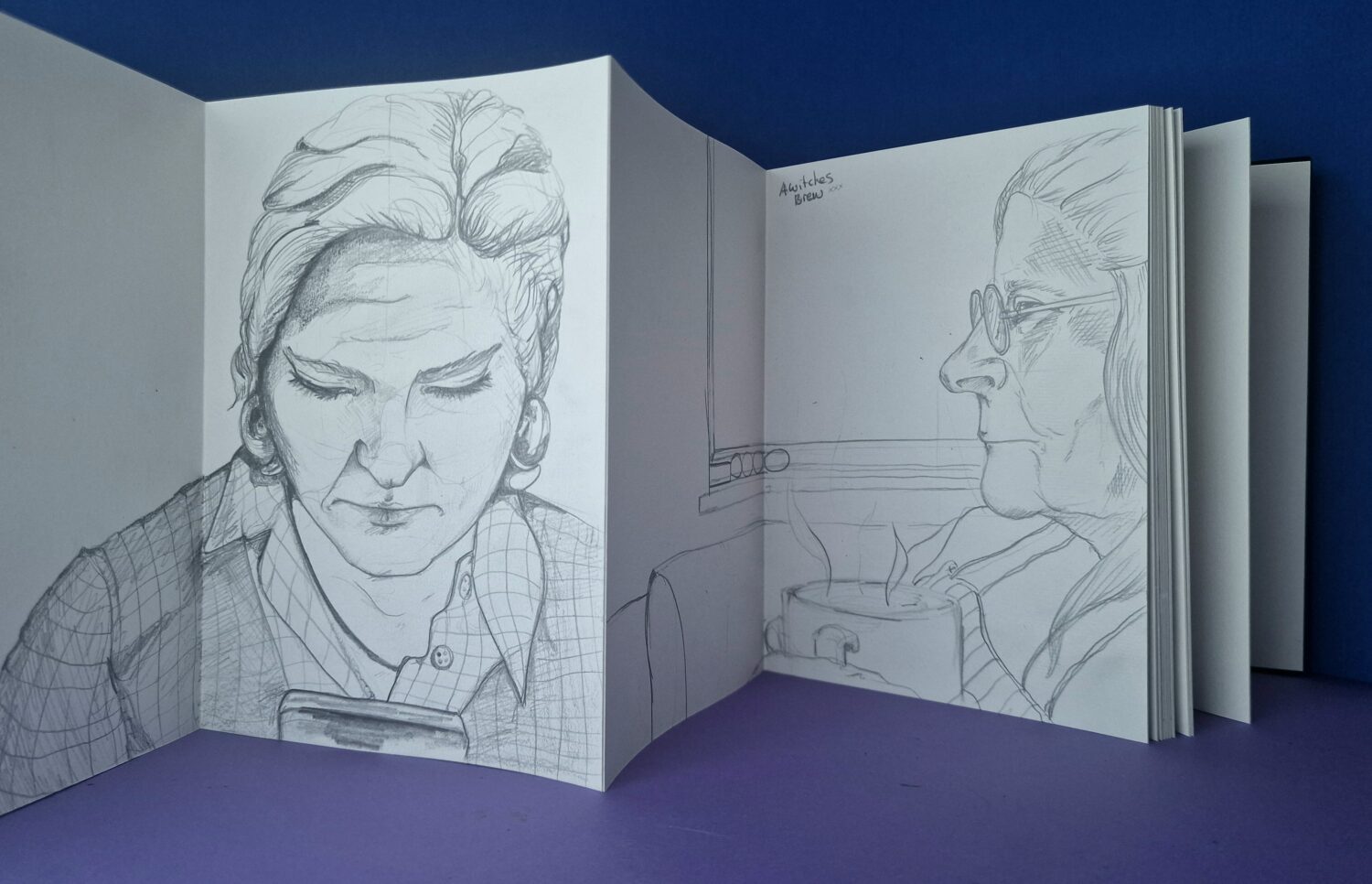 Sketches of heads on white card on a purple background.