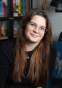 Image of a person with long brown hair and glasses smiling.