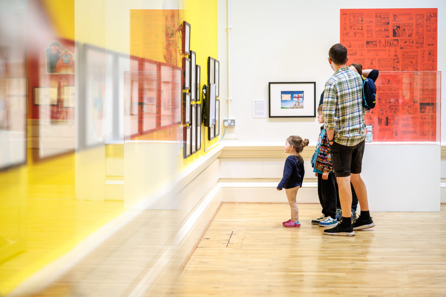 A family watching a TV screen in an exhibition.