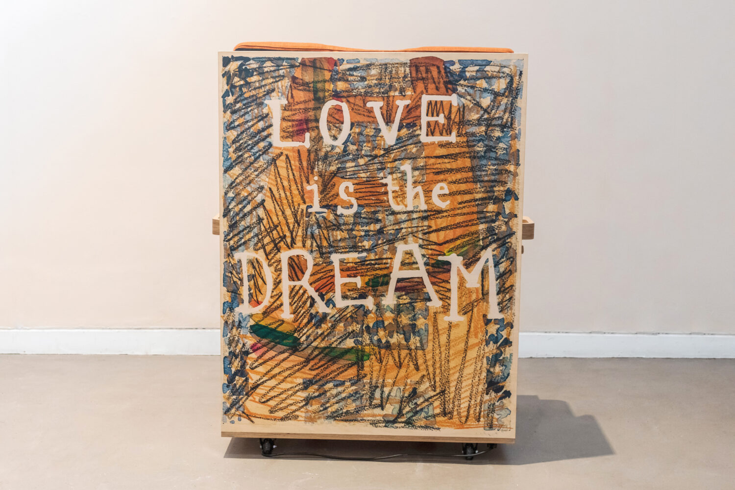 Large artwork on a wooden chair with writing ' Love is The Dream'