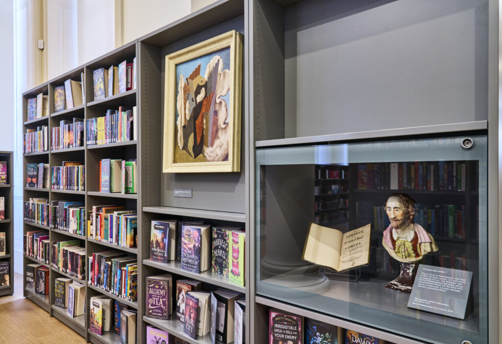 Image of a book shelf with a painting and Shakespere bust included.