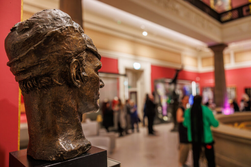 Image of people milling about and chatting near artworks.