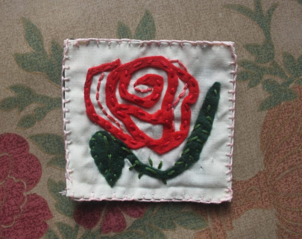 Image of a red rose on a white patch background.