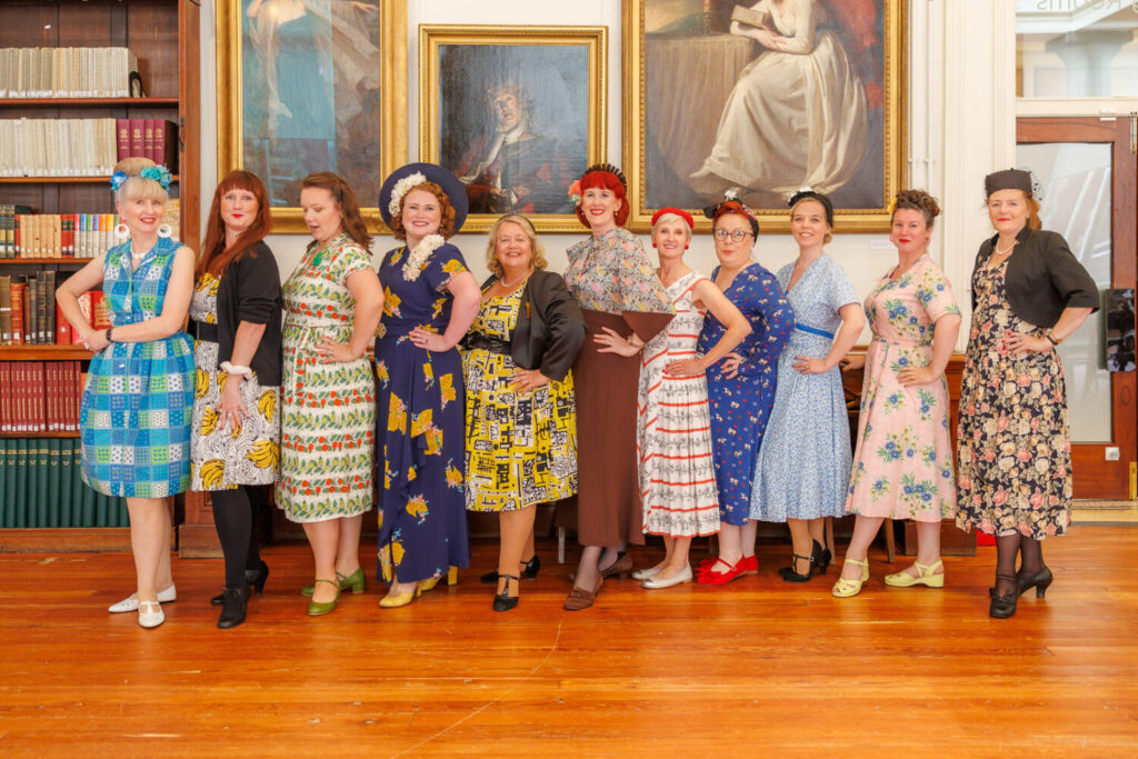 Image of ladies stood in a line wearing 1950s dresses.