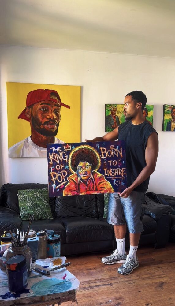 Picture of a person holding a bright colourful artwork with other paintings on the walls of influential black figures.