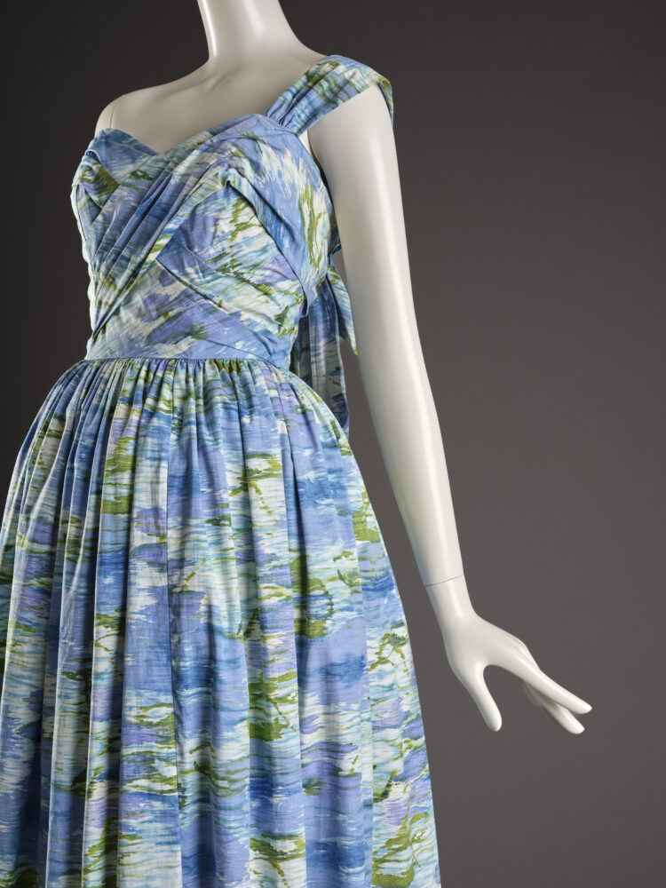 Image of a manniquin wearing a blue and green patterned long, off the shoulder, dress