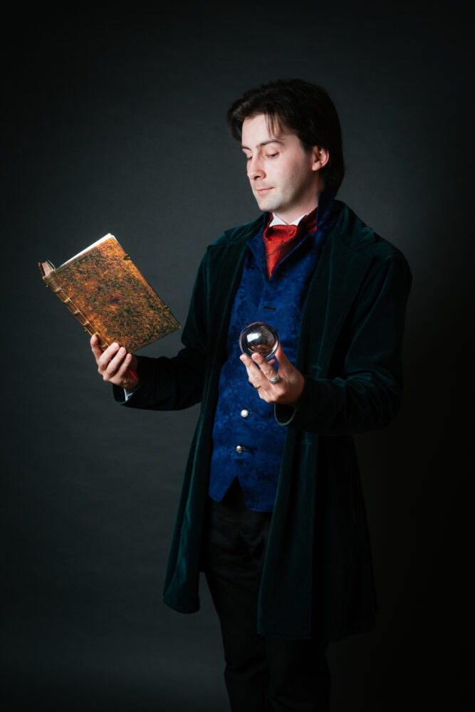 Image of a man holding a book and a glass ball